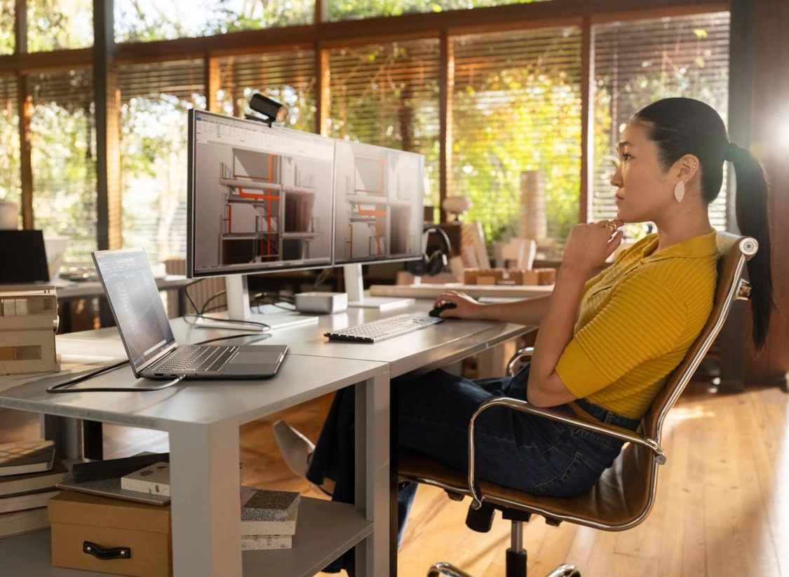 Professional working with an HP laptop and large monitor